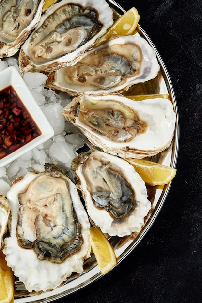 Oysters with lemon served on black round platter Luxury delicatessen seafood