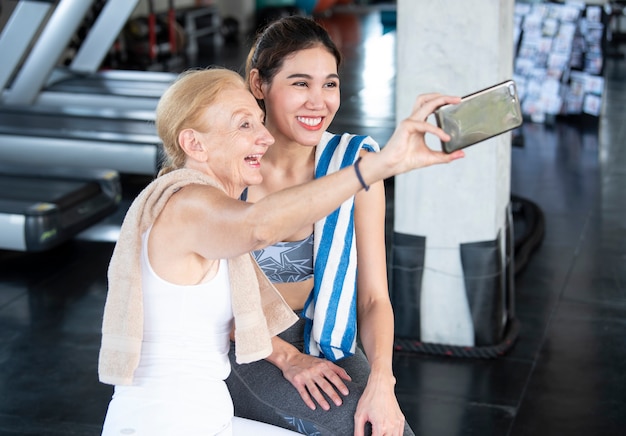 Paar aantrekkelijke vrouwen glimlachend nemen van een selfie op smartphone in sportschool fitness.