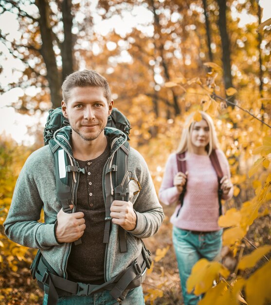 Paar Backpackers die door Autumn Forest lopen