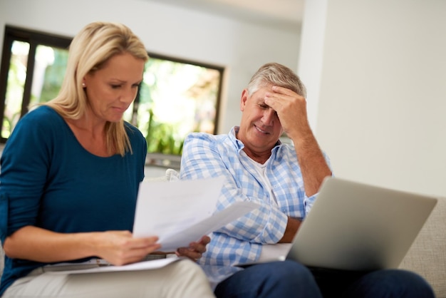 Paar bank en document met laptop en stress financiën of belastingen voor schulden in de lounge Papierwerk volwassen of man en vrouw persoon voor hypotheek overstuur en budget voor inflatie of faillissement in huis
