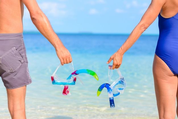 Paar bedrijf snorkelen masker in de hand te houden. Achteraanzicht, turquoise zee