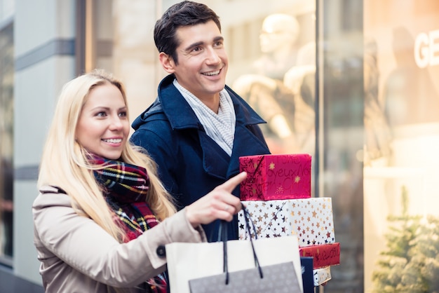 Paar bij etalage die het winkelen van Kerstmis doen