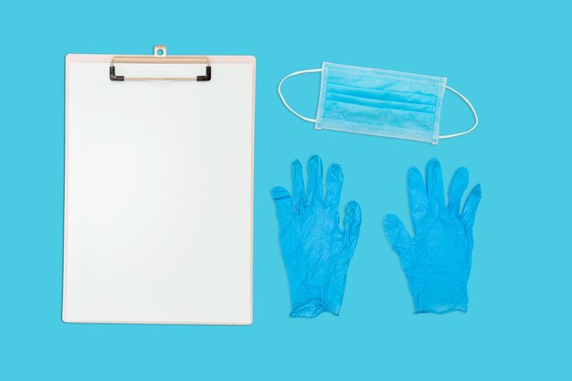 Paar blauwe medische handschoenen Blanco documentenmap Chirurgisch masker met rubberen oorbanden Typisch 3-laags chirurgisch masker om de mond en neus te bedekken Proceduremasker tegen bacteriën Beschermingsconcept
