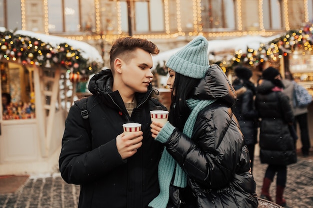 paar brengt samen tijd door op de kerstmarkt met warme dranken