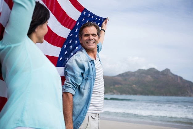 Paar dat Amerikaanse vlag op strand houdt