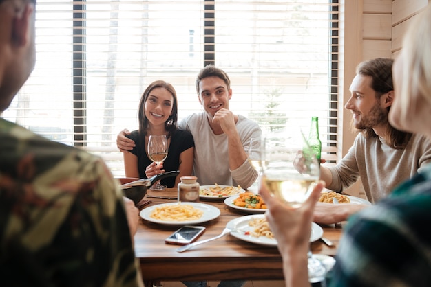 Paar dat diner heeft en met vrienden op de keuken spreekt