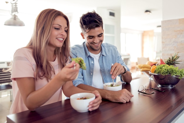 Paar dat een salade eet in de keuken