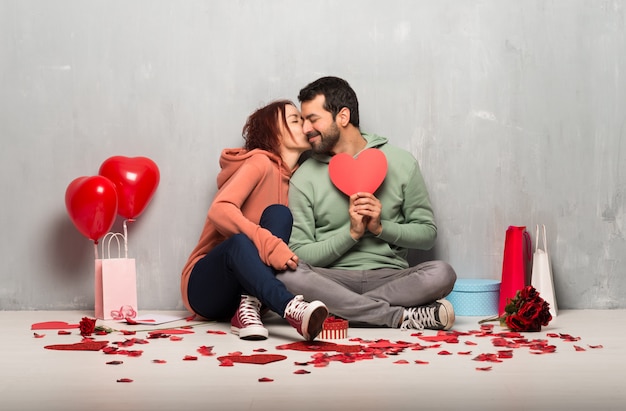 Paar dat in valentijnskaartdag een hartsymbool en het kussen houdt