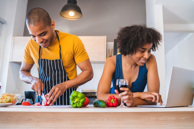 Paar dat laptop met behulp van terwijl het koken in keuken