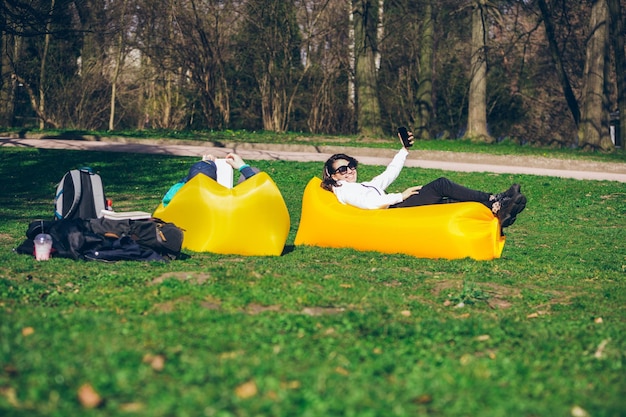 Paar dat op gele opblaasbare matras ligt in het leesboek van het stadspark en selfie neemt