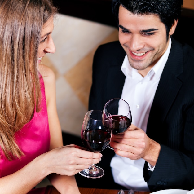 Paar dat rode wijn clinking glazen drinkt