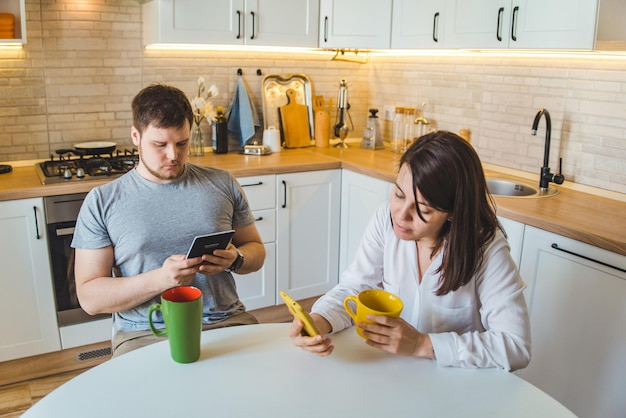 Paar dat 's ochtends in de keuken zit en thee drinkt en nieuws leest