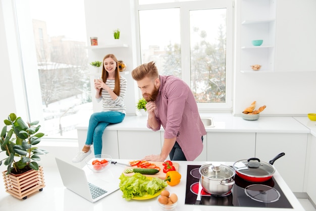 Paar dat thuis samen in de keuken met laptop zit