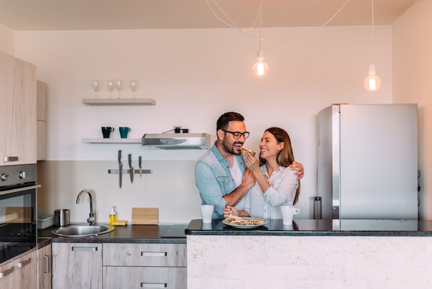 Paar dat zich in de keuken van moderne flat bevindt en samen ontbijt heeft.