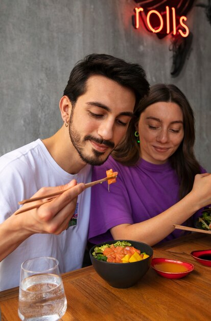 Foto paar die de kom van de zalmschotel eten bij het restaurant