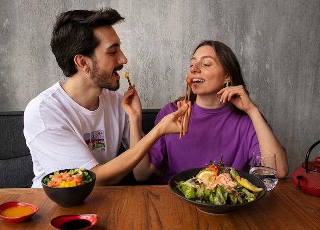 Foto paar die de kom van de zalmschotel eten bij het restaurant