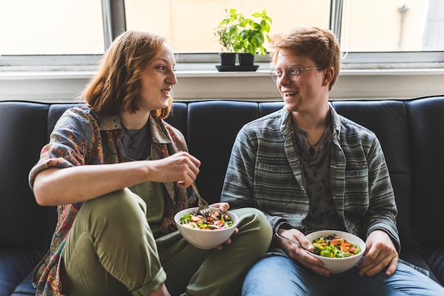 Paar die healty salade thuis op de bank eten