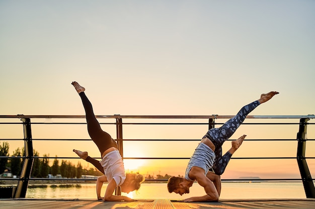 Paar doen samen yoga beoefenen op de natuur buiten ochtendoefeningen bij de zonsopgang