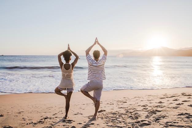 Paar doet yoga op het strand