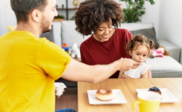 Paar en dochter ontbijten zittend op tafel thuis