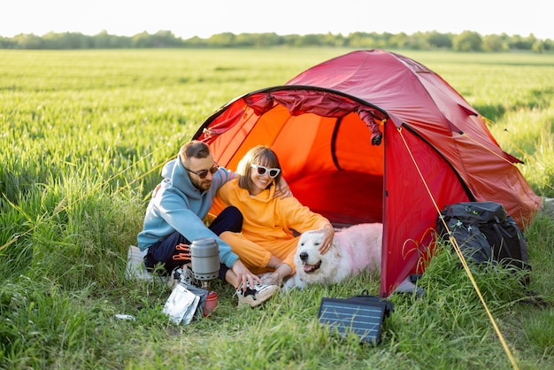 Paar en huisdier op camping met tent op een groen veld