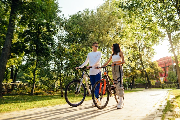 paar fietsers in casual outfits lopen in het stadspark met hun kleurrijke fietsen