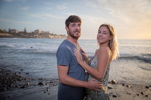 Paar geliefden op het strand tijdens zonsondergang knuffelen en worden verliefd Aantrekkelijke jongen en meisje knuffelen Partners hebben plezier op het strand Saamhorigheid en geluk concept Valentijnsdag viering