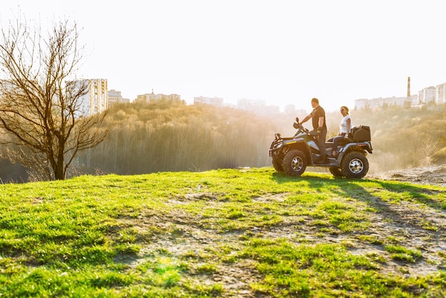 Paar geniet van het rijden op een ATV op bosheuvels bij zonsondergang