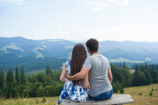 paar genieten van het uitzicht op de bergen zittend op een bankje