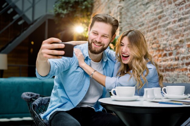 Paar genieten van tijd samen, selfie maken, aan café tafel zitten en koffie drinken.