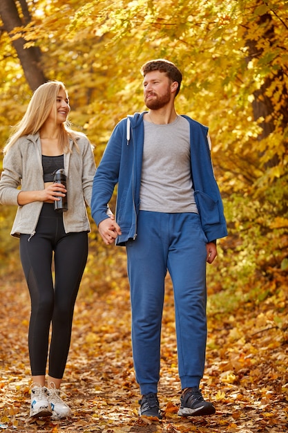 Paar genieten van wandelen in het zonnige herfstbos, de natuur, gele bomen rond overweegt. wandelen, herfstbos, wandelen, liefdeconcept