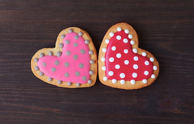 Paar gestippelde hartvormige royal icing cookies op zwarte houten achtergrond