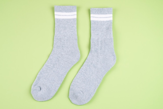 Foto paar grijze sokken met witte strepen op lichtgroene pastelachtergrond, bovenaanzicht. hoge kwaliteit foto