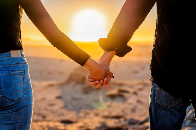 paar hand in hand bij zonsondergang