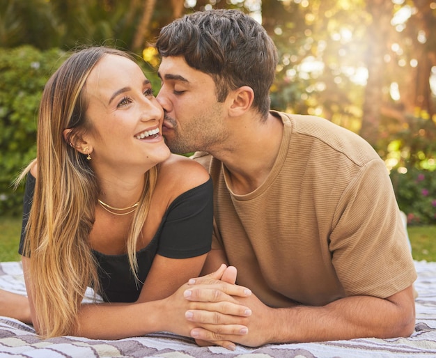 Paar hand in hand met kus en liefde in de parkpicknick voor hechting en gelukkig samen in de natuur Ondersteun vertrouwen en zorg met romantische date en outdoor leuke toewijding en geluk