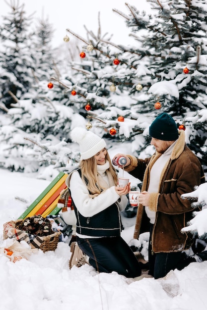 paar in de winter die thee drinkt in dennenbos