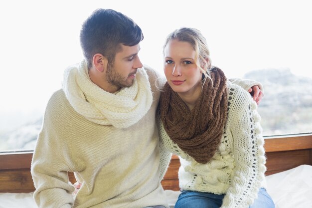 Paar in de winter kleding zittend tegen raam