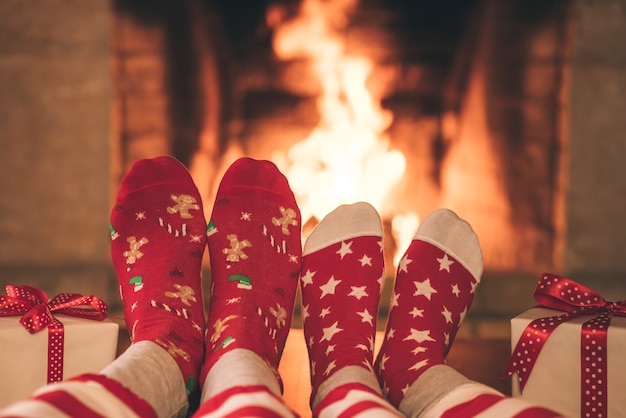 Paar in kerstsokken bij open haard Man en vrouw hebben samen plezier