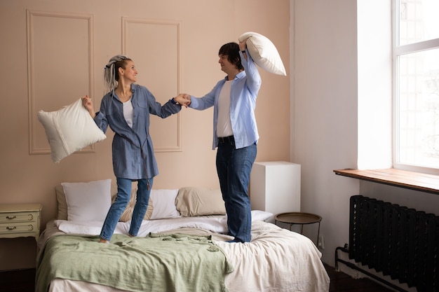 Paar in slaapkamer spelen kussens vechten op bed. Samen tijd doorbrengen.