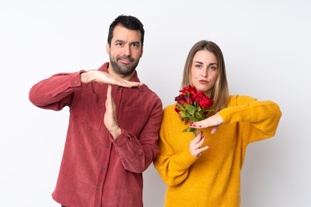 Paar in Valentijnsdag bedrijf bloemen over geïsoleerde muur maken stop gebaar met haar hand om een handeling te stoppen