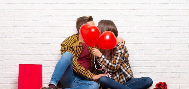 Paar in valentijnskaartdag bij binnen met ballons met hartvorm