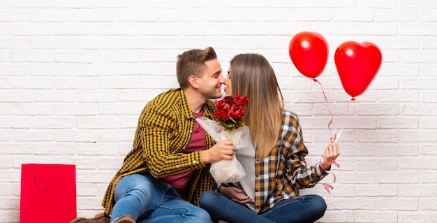Paar in valentijnskaartdag bij binnen met bloemen en ballons met hartvorm