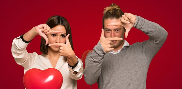 Paar in valentijnskaartdag die gezicht concentreert. Kadersymbool over rode achtergrond