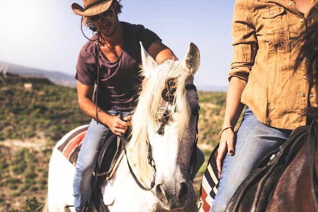 Paar jonge alternatieve duizendjarige man en vrouw die paard rijden in de natuur - vrijetijdsbesteding in de buitenlucht voor mooie mensen met dieren