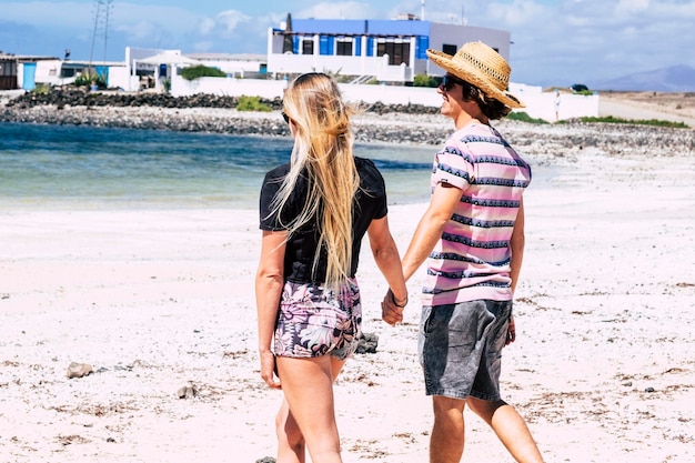 Paar jonge meisje en jongen in toeristische vrijetijdsbesteding wandelen op het strand in liefde en relatie gelukkige mensen genieten samen van zomervakantie vakantie in tropische bestemming paar reizen