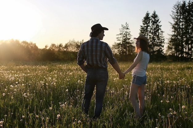 Paar jonge mensen wandelen in de zonsondergang lenteavond in veld