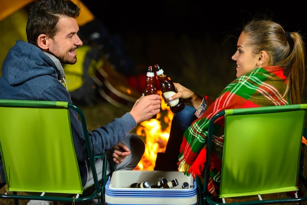 Paar kampvuur tijdens het kamperen bier drinken