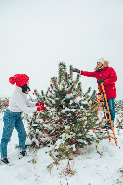 Paar kerstboom versieren buitenshuis gesneeuwde winter buitenshuis