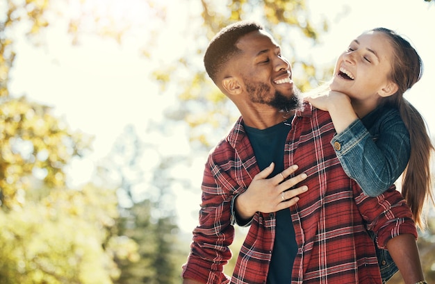 Paar knuffelen en glimlachen terwijl ze buiten zijn met liefde en zorg in de natuur gelukkig samen terwijl ze zich hechten in het park Zwarte man vrouw en interraciaal knuffelen in relatie en huwelijk met romantiek mock up