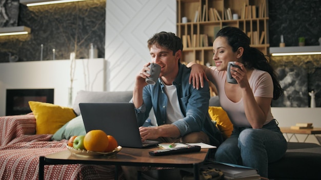 Paar koffie drinken thuis woonkamer kijken op laptop gelukkige familie avond